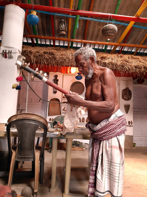Bahadur's father dusting an old Indian musical instrument from rare collection of folk arts of Bengal and other Eastern Indian states: Bahadur Chitrakar, the artist behind this collection in the remote  village of Nayagram, East Midnapore District, West B