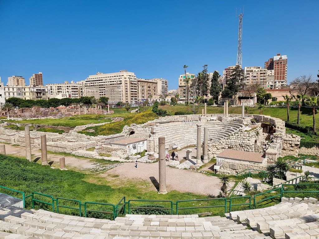 A photo of the Amphitheathre and the Roman ruins around it, taken from above. The archaeological site is surrounded by tall residential buildings