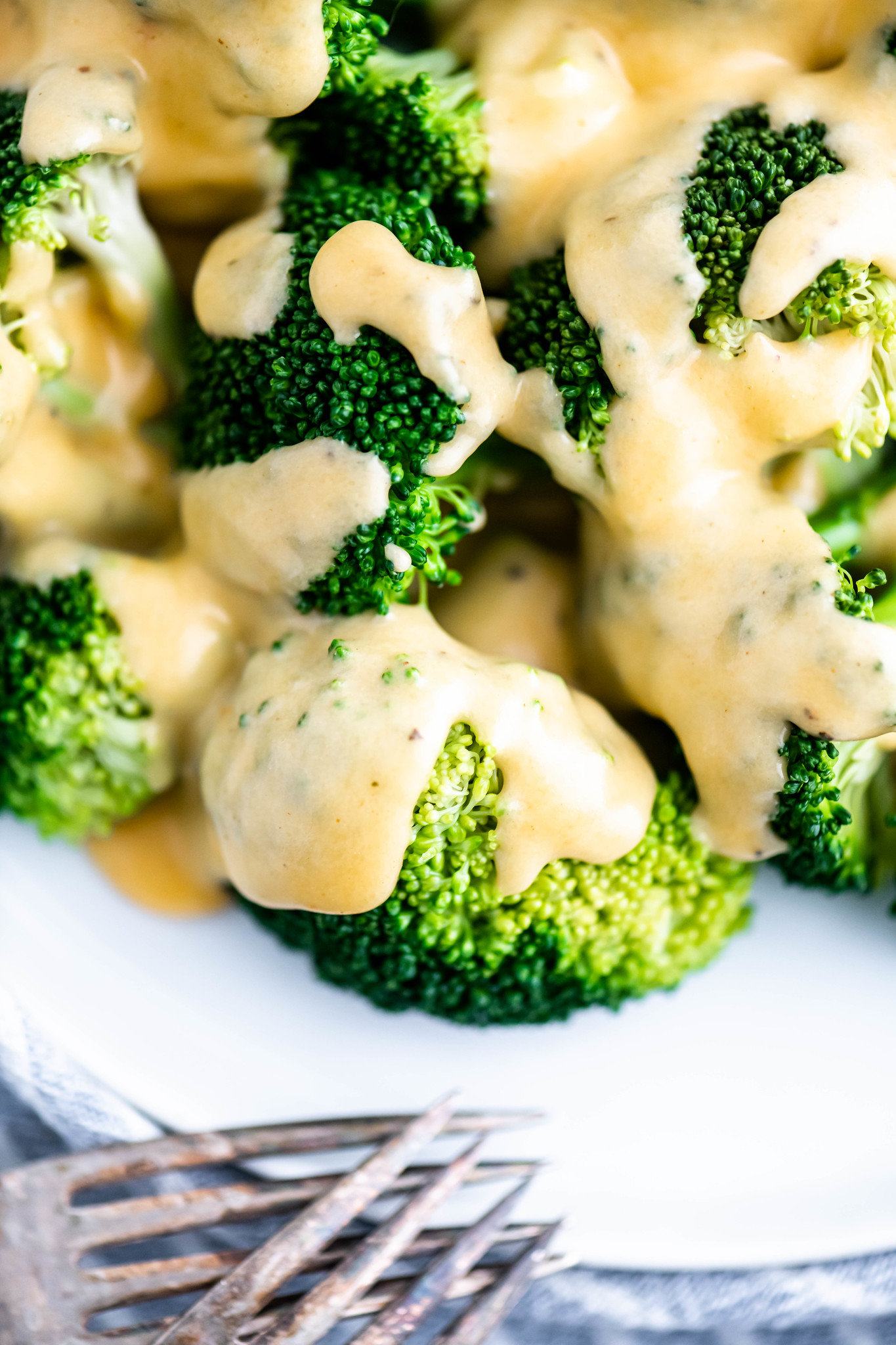 Close up of broccoli covered in cheese sauce.