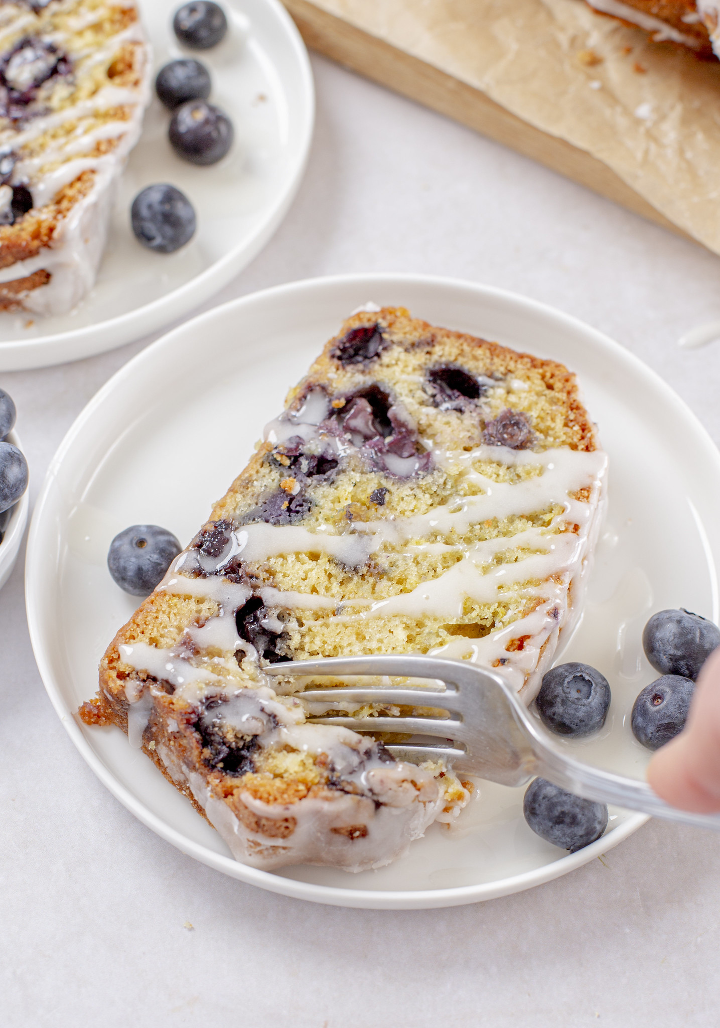 Slice of blueberry lemon loaf cake on a plate with glaze drizzled on top