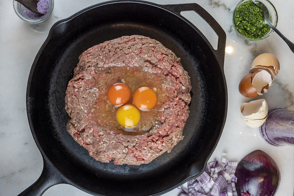 Preparation of a meatloaf with eggs, and spices, in a cast iron pan for roasting