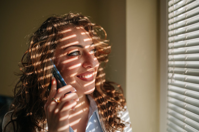 Smiling woman making a phone call while looking out of the window