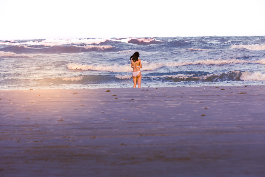 A female subject stands along the seashore of the Gulf of Mexico in Corpus Christi, Texas at sunset.