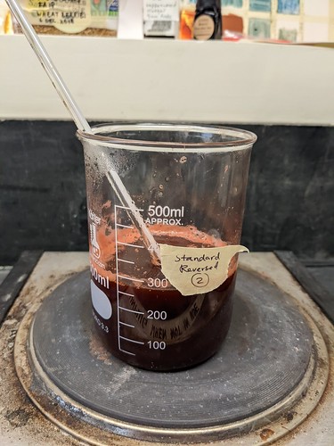 Standard Reversed 2 beaker is on stovetop, halfway full of reddish liquid and no drawstring bag