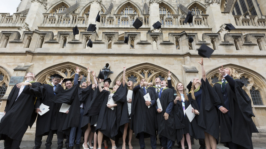 Graduates throw caps in the air outside Bath Abbey