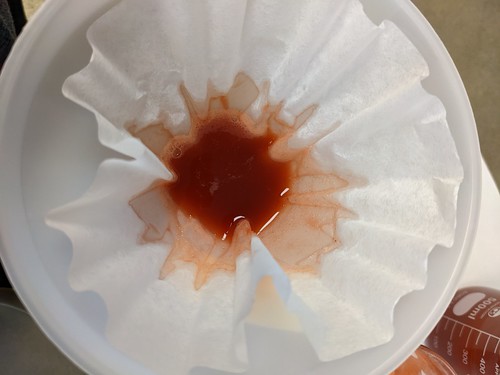 Overhead shot of reddish liquid draining in filter