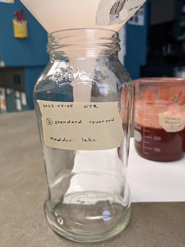 Funnel containing filter is positioned over an empty glass jar labeled 2 Standard Reversed Madder Lake