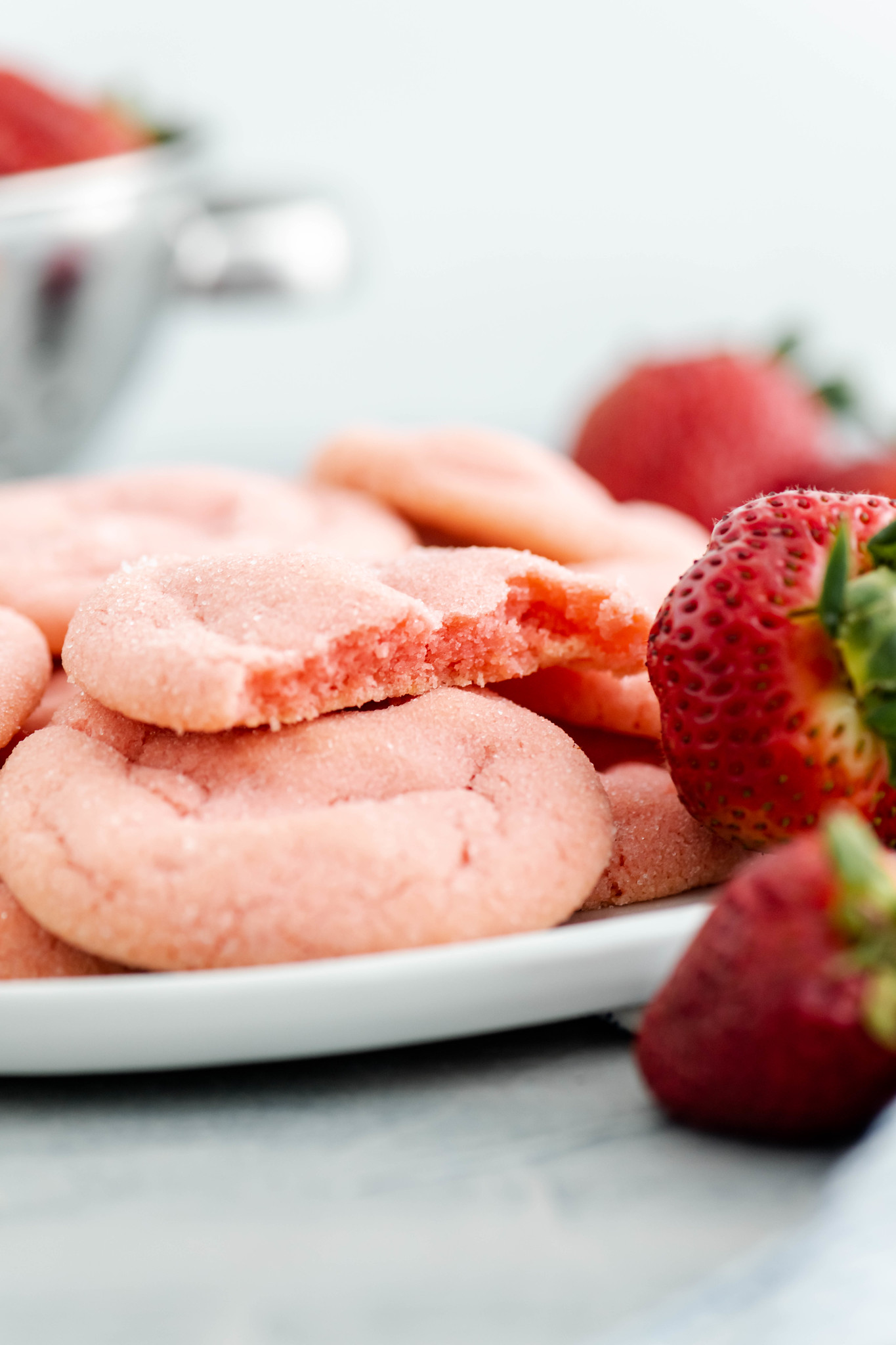 White round plate piled with strawberry cookies. One cookie broken in half to show inside.