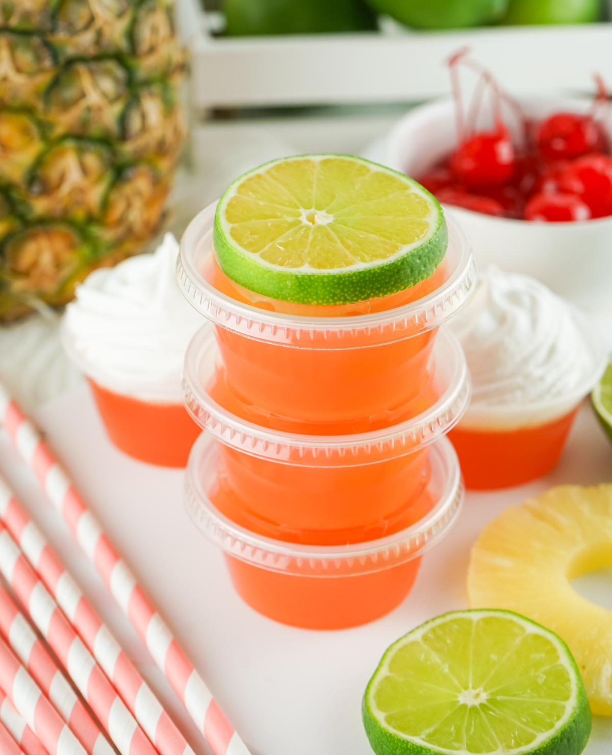 3 orange jello shots stacked on top of each other with a lime slice on top