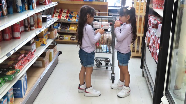 The twins enjoy lollipops while mom shops.