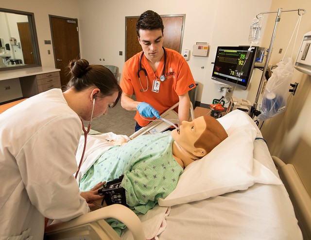 Students treat a “patient” in a simulation room