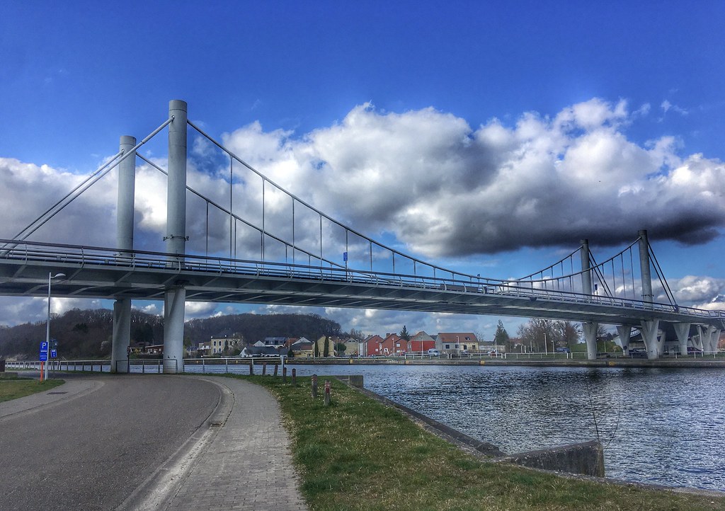 Clouds from the sky over an iconic bridge near Kanne in Belgium -street view near the water-