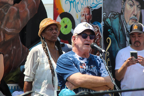 Quint Davis speaks in front of Charmaine Neville at the ceremony unveiling ancestor monuments for Charles and Art Neville at Jazz Fest 2022. Photo by Katherine Johnson.