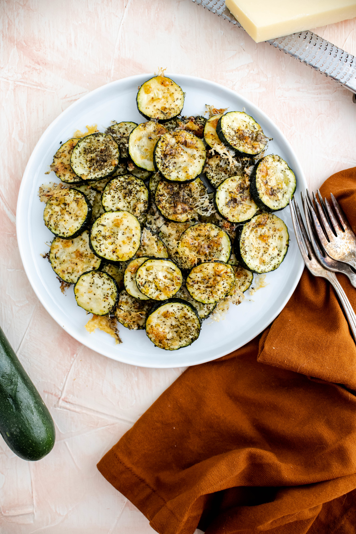 Round white plate filled with parmesan zucchini slices.