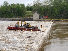 Photo of barge floating over the top of a dam in flooded water