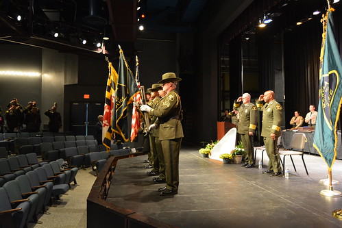 Photo of officers and color guard on stage saluting the flags of the United States, Maryland, and the Maryland Natural Resources Police
