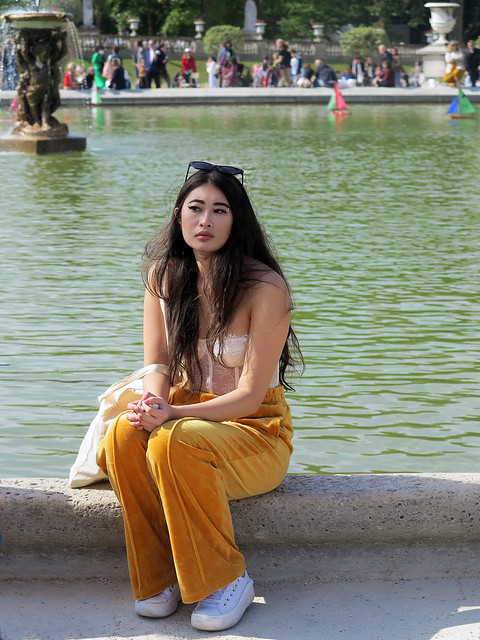 Beautiful Asian girl sitting at the edge of the Luxembourg garden grand pond