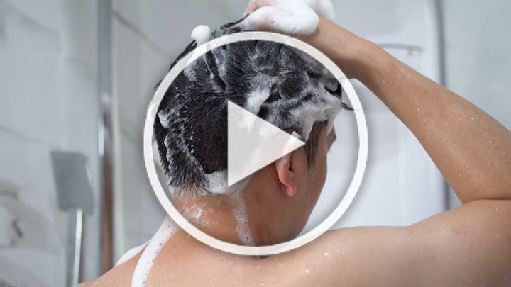 A woman washing her hair with lots of shampoo