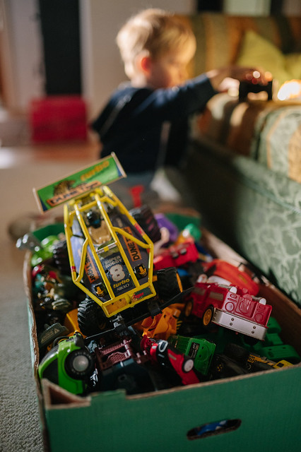 A box full of toy cars and a boy playing in the blurry background