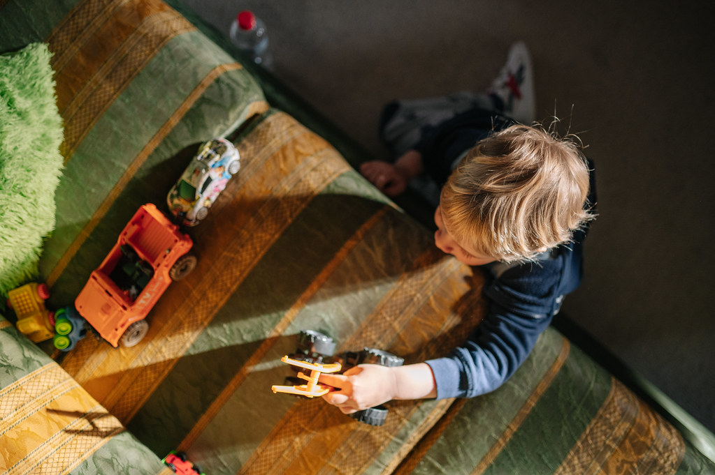 Boy playing with his toy vehicles on the couch