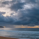 24. Aprill 2022 - 7:03 - Sunrise at the seaside with rain clouds at Killcare Beach on the Central Coast, NSW, Australia.