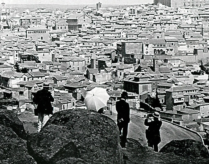Personajes con sombrilla y sombrero usan una cámara en las inmediaciones de la piedra del Rey Moro en Toledo en 1907. Fotografía de F. Bardon (detalle)
