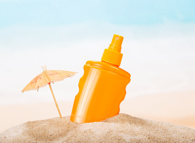 Bottle of sunscreen in the sand against  sea.