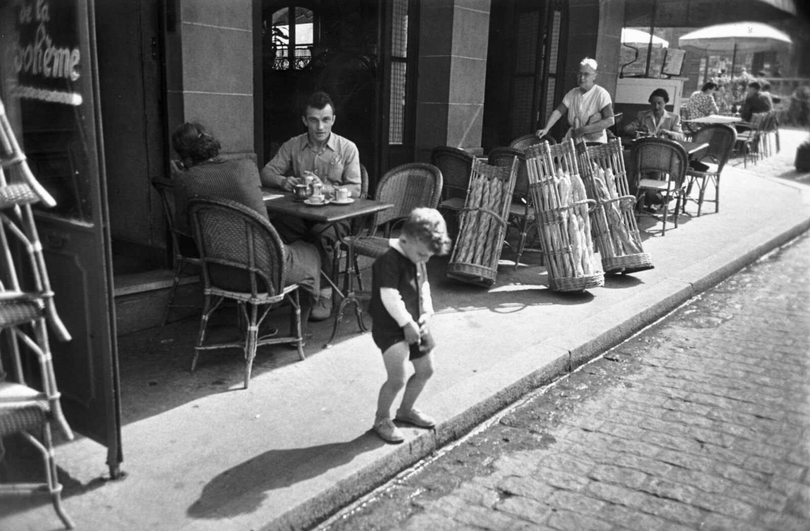 1950. Мальчик на Монмартре пользуется водостоком возле кафе, чтобы справить нужду