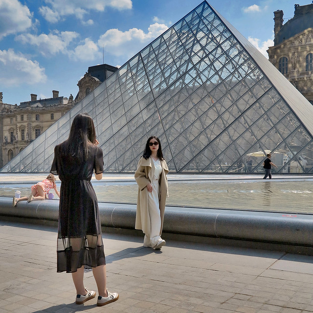 Asian girls photographing themselves in front of the Louvre pyramid