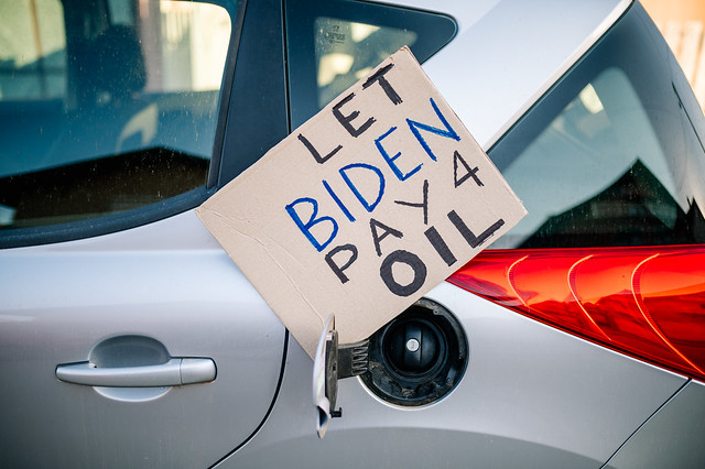 Sign with text 'Let Biden Pay 4 Oil' left on a car's open fuel door