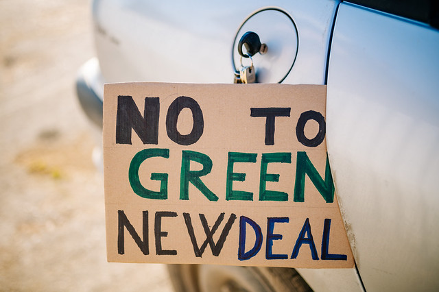 Sign with text 'NO to Green New Deal' left stuck in a car's rear door next to the fuel cap