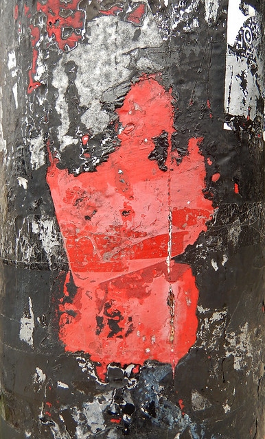 tape on a red lamppost that has been painted black