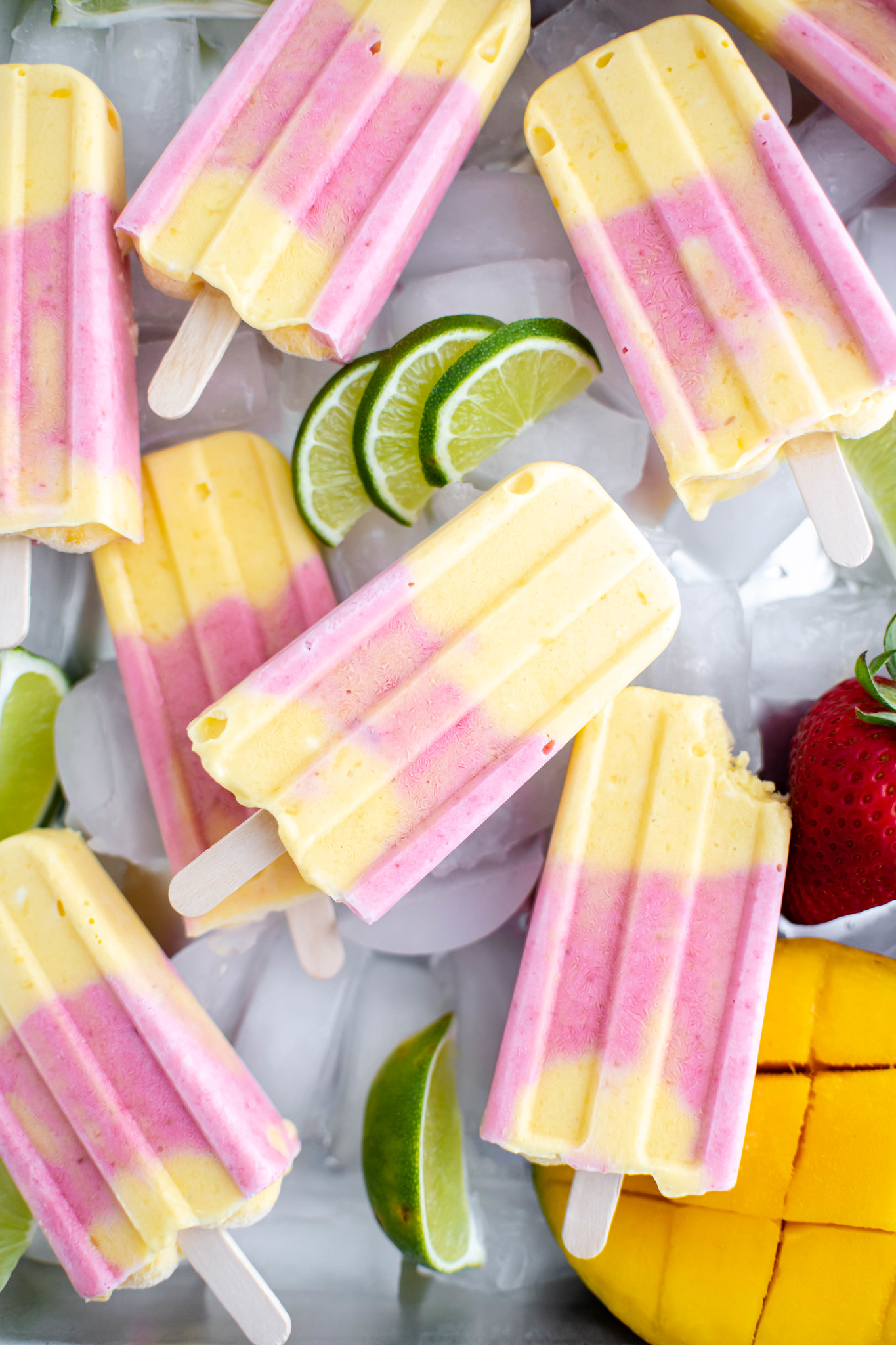 Silver tray topped with a layer of ice then a pile of strawberry mango popsicles.