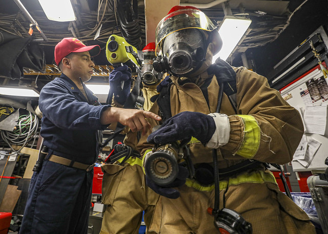 Chief Damage Controlman Carlos H. Rodriguez, left, provides training to Damage Controlman Fireman Ethan Heffner, center, and Fireman Alexander Mena, right) in the general workshop of USS Benfold (DDG 65) during a firefighting drill.