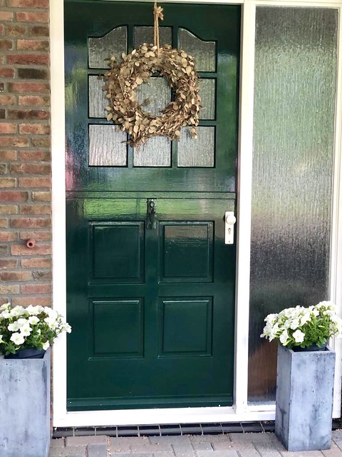 Groene landelijke voordeur met krans grijze potten met witte petunia's