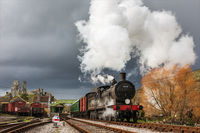 Ex-LSWR Drummond T9 4-4-0 no. 30120 leaves storm clouds behind as it makes a brisk departure from Corfe Castle with a southbound local train on 21st March 2014