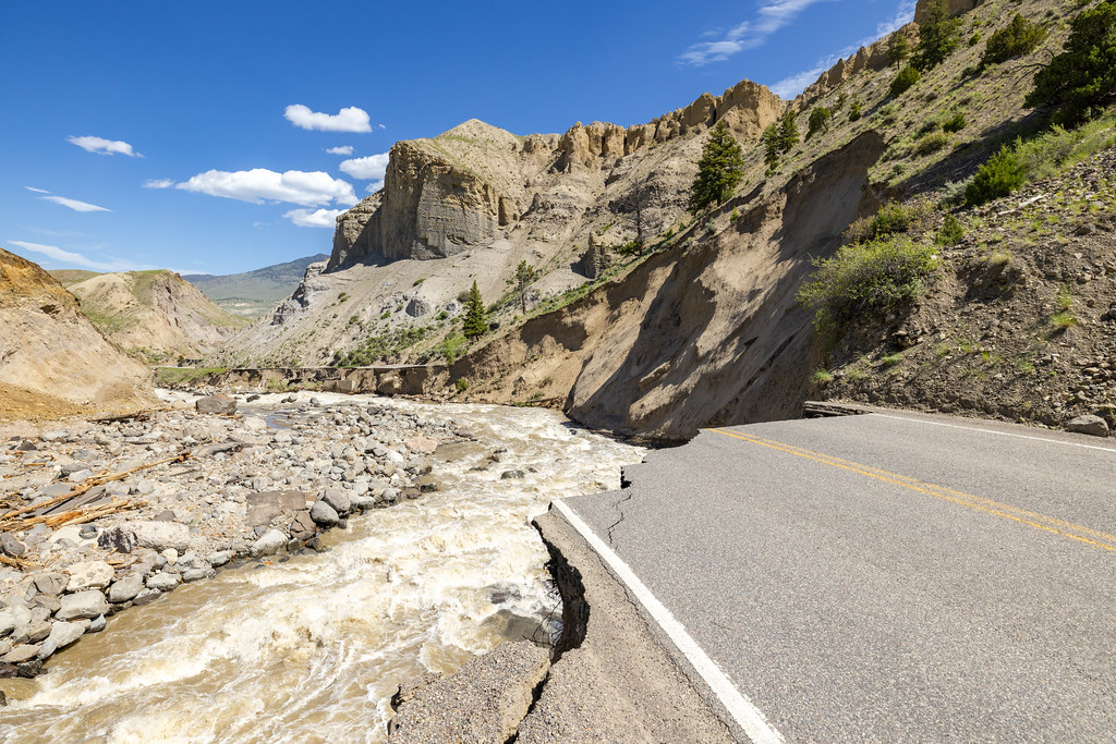 A paved road near a river in a canyon that was completely damaged in a flood.