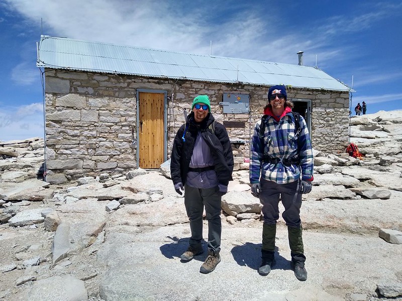 The cousins posing with the Smithsonian Summit Hut on top of Mount Whitney, at the end of the John Muir Trail