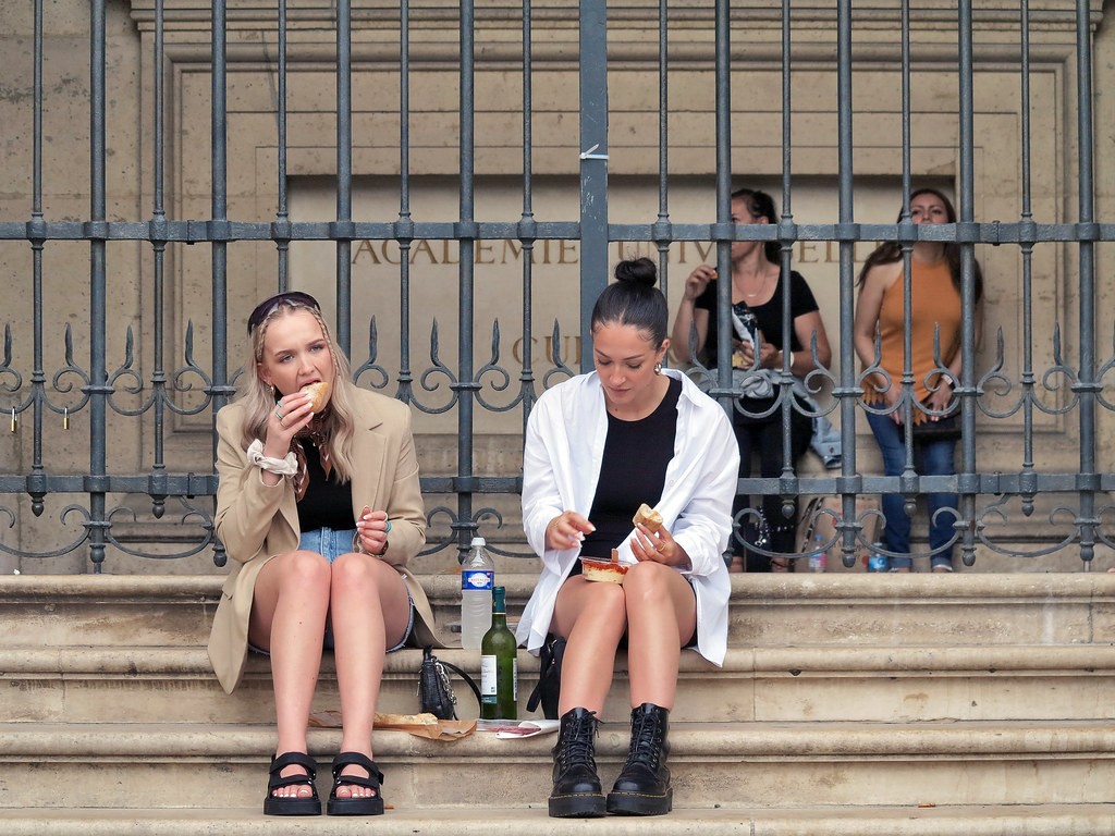 Four young women having a snack sitting in front of the Louvre University Academy of Culture