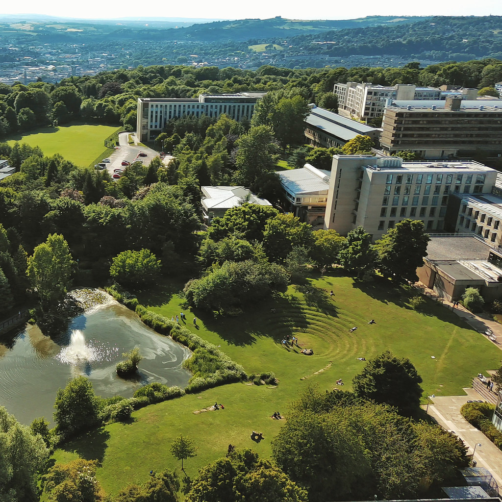 An aerial image of the University of Bath campus, including a lake and buildings.