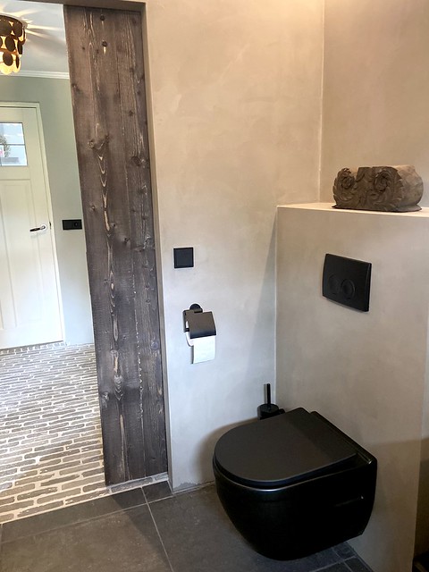 Houten schuifdeur landelijke badkamer waaltjesvloer hal zwart toilet houten ornament