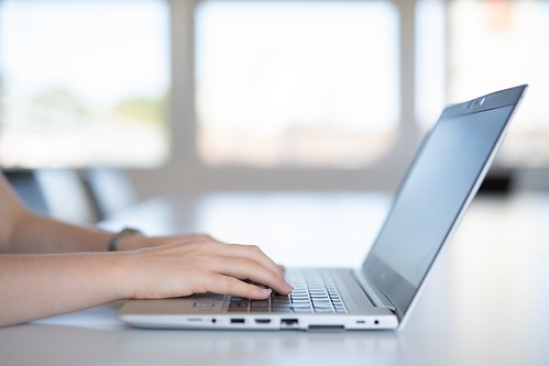 Close-up of hands typing on a laptop keyboard - Most Common College Essay Topics