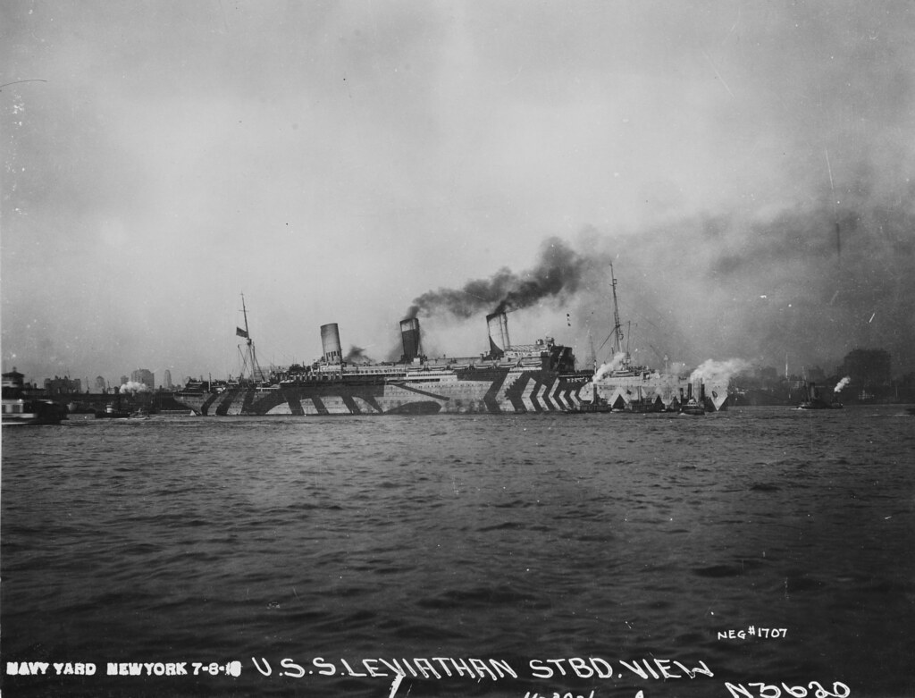Troopship USS Leviathan  (ID1326) In New York Harbor, 8 July 1918, wearing dazzle camouflage and attended by several tugs.