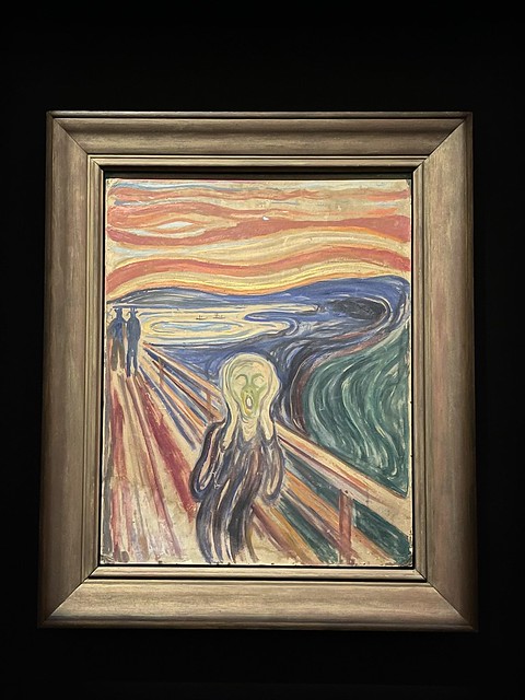 Edvard Munch's "The Scream" in a wooden frame on a black background.