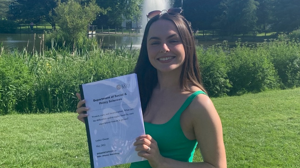 Amber, in front of the lake, holding her dissertation
