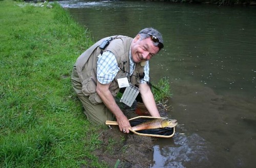 Photo of man in a stream holding a fish in a net