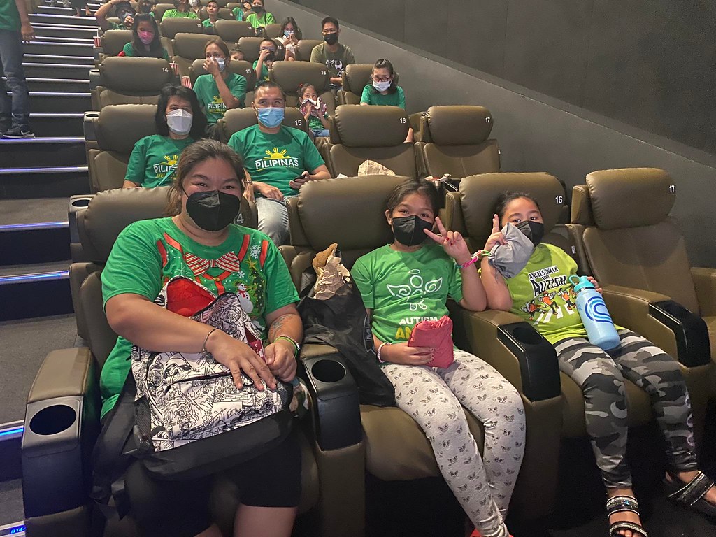 ASP Family having fun watching Lightyear Movie with face masks on. Two kids doing peace signs.