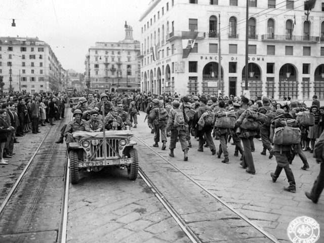 SC 337141 - 92nd Div. troops riding down street in newly-liberated Genoa pass PWs going to the rear. 21 April, 1945.