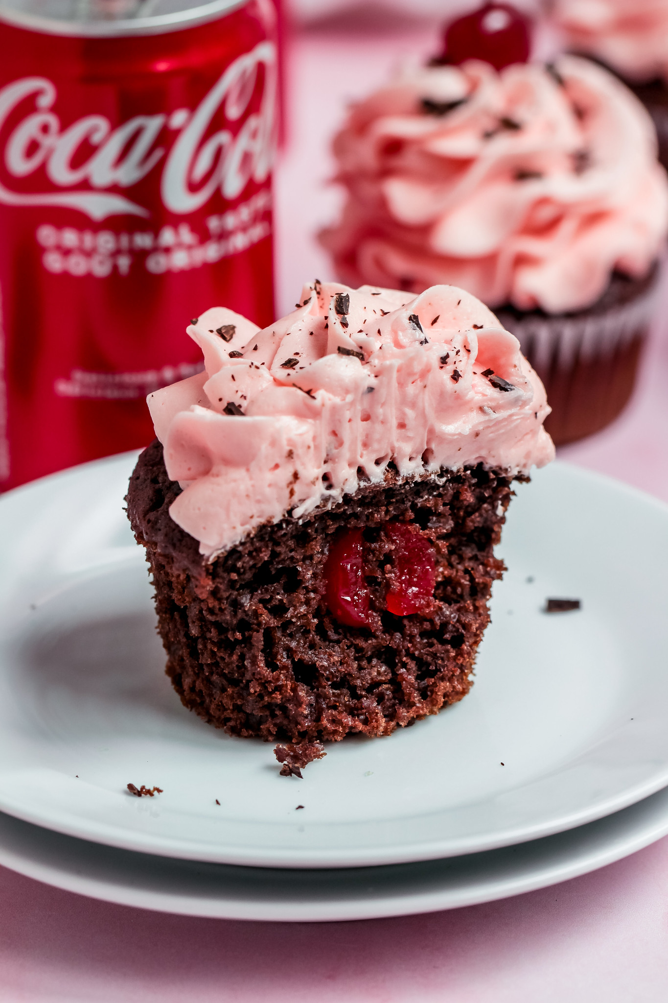half of a chocolate cupcake with a cherry in the center and pink frosting. 