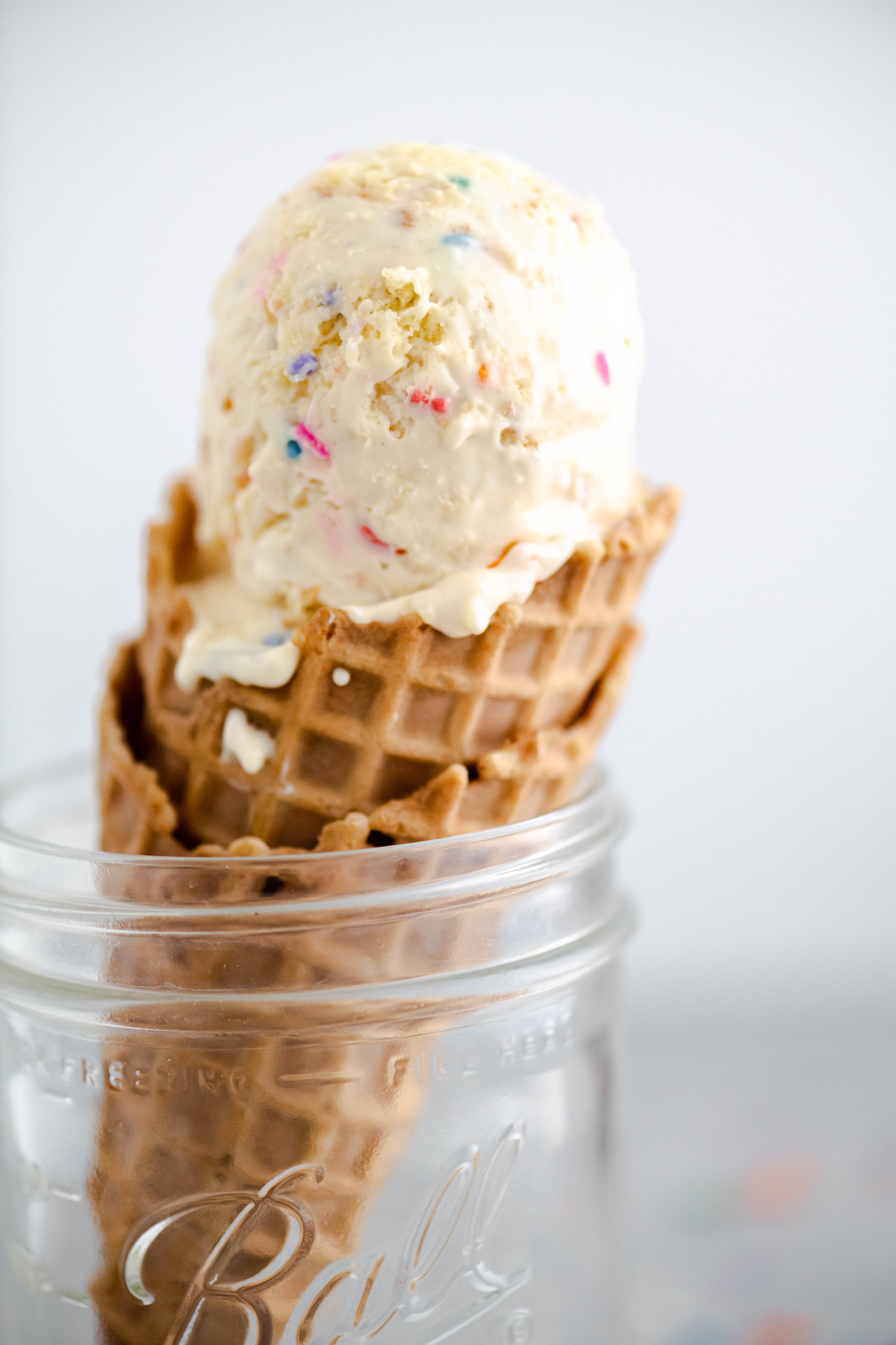 Waffle cone filled with cake batter ice cream placed in a mason jar.